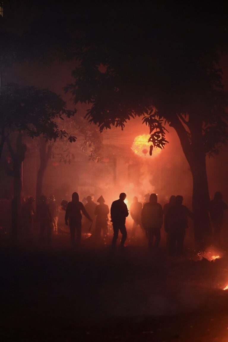 People gather at night with a fiery, orange glow.